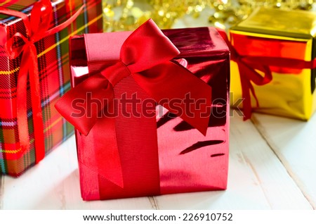Christmas gifts wrapped in bright red and chequered pack paper decorated with red ribbon 