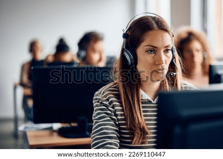 Mid adult student wearing headset while e-learning during computer class in the classroom.