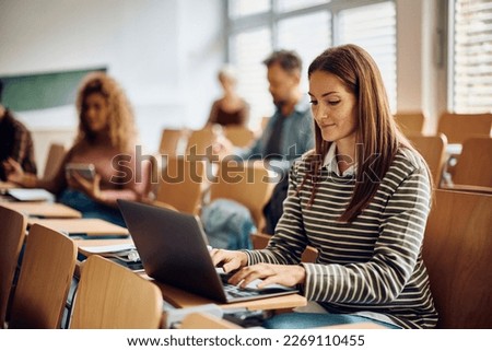Smiling mid adult woman using laptop during a lecture at the university. Royalty-Free Stock Photo #2269110455