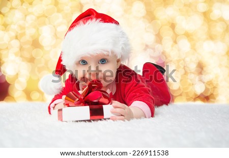 Beautiful little baby celebrates Christmas. New Year's holidays. Baby in a Christmas costume with gift