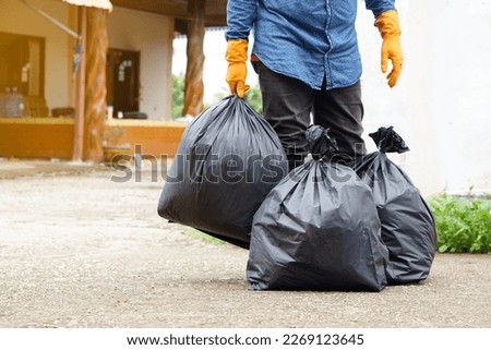 Closeup man holds black plastic bag that contains garbage inside. Concept , Waste management. Environment problems. Daily chores. Throw away rubbish .                         Royalty-Free Stock Photo #2269123645