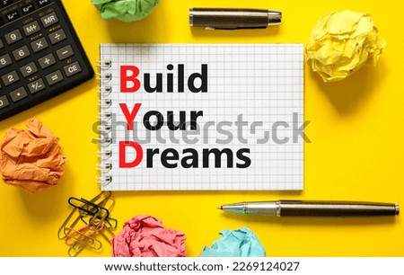 BYD build your dreams symbol. Concept words BYD build your dreams on white note on a beautiful yellow background. Black pen. Calculator. Business and BYD build your dreams concept. Copy space.