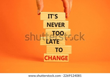 Change symbol. Wooden blocks with words 'It is never too late to change'. Businessman hand. Beautiful orange background, copy space. Business and It is never too late to change concept.