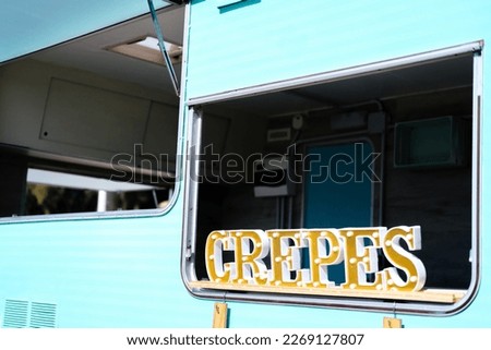 Blue and white caravan transformed into food truck with crepes sing