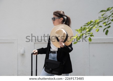 young happy brunette girl in sunglasses and straw hat with a suitcase, vacation