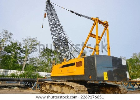 The yellow crawler crane is being parked in the oil and gas rig area after being used. Royalty-Free Stock Photo #2269176651