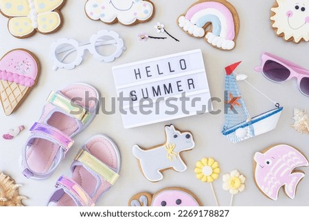 Hello summer text on lightbox and cute summer symbols on grey background. Top view, Flat lay. Creative summer concept, greeting card.
