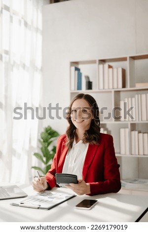 Confident business expert attractive smiling young woman typing laptop ang holding digital tablet  on desk in creative office.