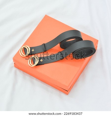 Photo of a two black belt on an orange box, shot from a eye level angle