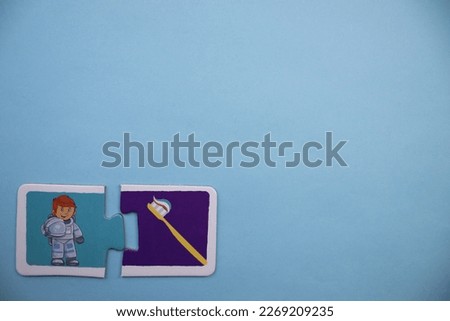 Colorfully colored astronaut and toothbrush, picture puzzle pieces placed at lower left of blue background.