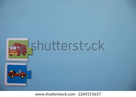 Colorfully colored puzzle pieces with pictures of firefighter car and small car placed at lower left of blue background.