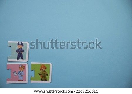 Multicolored puzzle pieces with pictures of doctor, fireman and policeman, mixed in the lower left of the blue background.