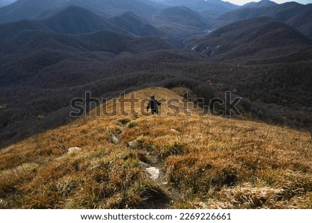 A man going hiking in the Caucasus mountains. A young man with a backpack descends from the top of the mountain. A tourist in the mountains. A young man on top of a mountain enjoying nature. 
