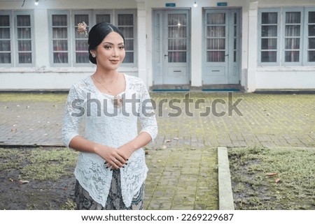 A young Indonesian woman with a happy successful expression wearing a white kebaya. Kartini's Day Concept.