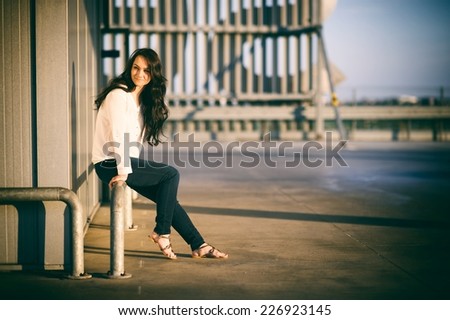 Girl sitting on railing at sunset light