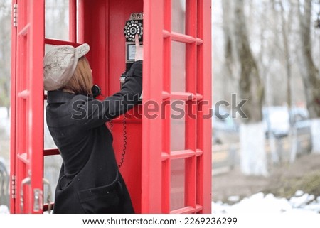 Beautiful young girl in a phone booth. The girl is talking on the phone from the payphone. English telephone booth in the street and a woman talking on the phone.
 Royalty-Free Stock Photo #2269236299