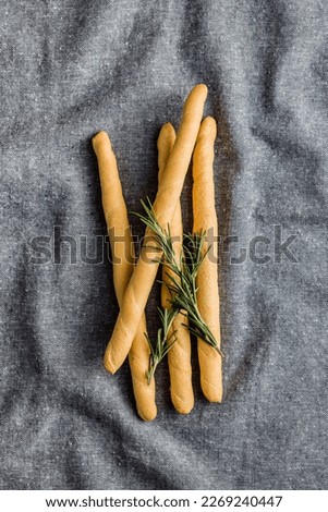 Italian grissini bread sticks and rosemary on the kitchen tablecloth. Top view.