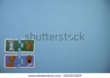 Educational puzzles with picture of rabbit, carrot, dog and kennel placed on left over blue background.