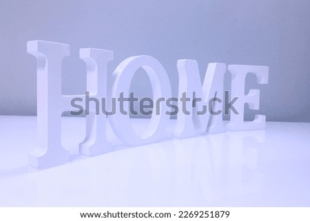 The word "home" in white made of wood is on a shelf in the living room or kitchen, blue-tinted photo