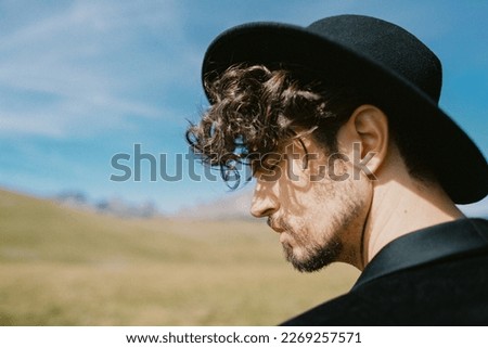 Profile of a young man in a hat against the backdrop of mountains. Portrait