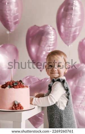 Cute little girl, 1st birthday, baby with pink heart balloons and birthday cake