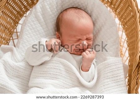 Crying baby 1-2 months old wake up in crib with stomach colic pain lying in bedtime closeup. Childhood.  Royalty-Free Stock Photo #2269287393