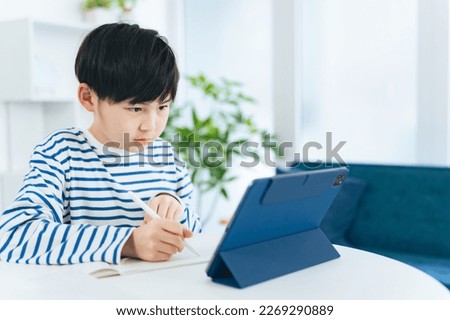 Asian little boy studying while looking at a tablet. Online class. e-learning. Ed tech. Royalty-Free Stock Photo #2269290889