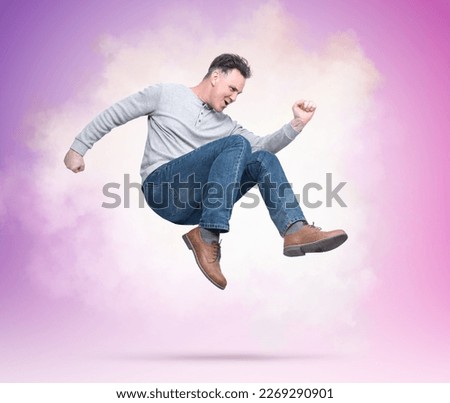 Funny man in everyday clothes makes a dance style on a pink with a purple background
