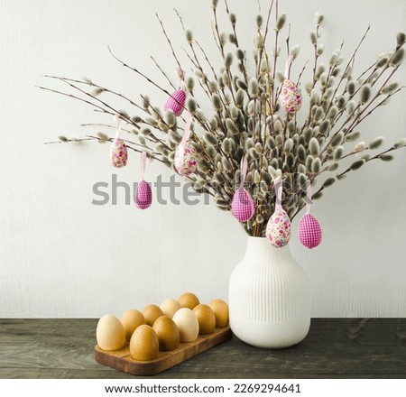 Decorative Easter composition in natural ecological style.  On a wooden table is a white vase with willow branches and Easter eggs.  Front view, bright easter holiday concept.