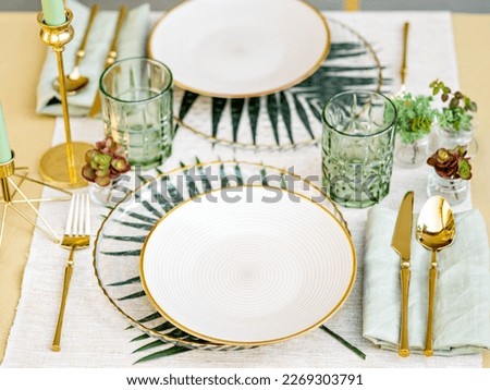 Sophisticated floral table setting. white crockery, golden cutlery and white table linen make a luxury setting. The formal elegant composition is perfect for a birthday banquet, a date or a wedding.  Royalty-Free Stock Photo #2269303791