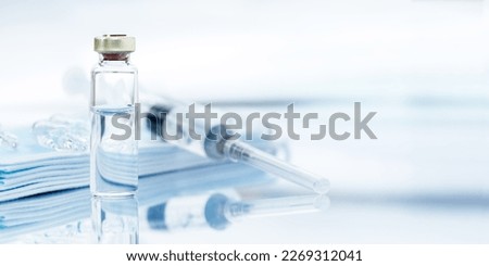 Medical mask, syringe and ampoules over desk close up and copy space. Royalty-Free Stock Photo #2269312041