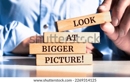 Close up on businessman holding a wooden block with "Look at bigger picture" message