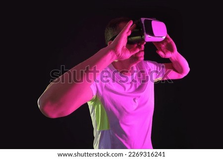 Sporty mature man using VR glasses on dark background