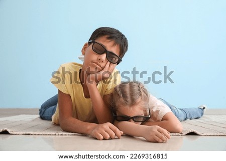 Sleeping little girl and her brother in 3D glasses near blue wall