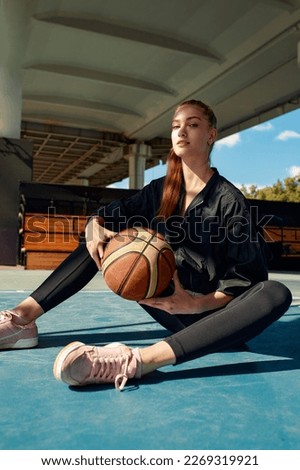 Pretty young girl posing with a basketball in a park