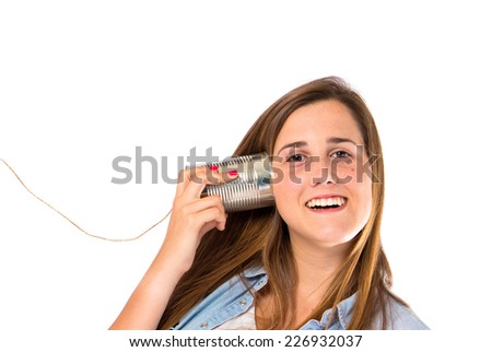 Girl listening through a tin phone over white background