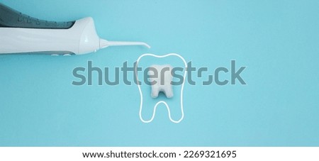 Irrigator near tooth model with protective vortex on blue background, professional clean teeth, teeth will good healthy