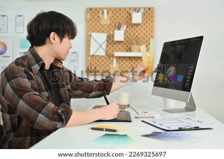 Side view of young man UX graphic designer working together for mobile application software design project at workstation