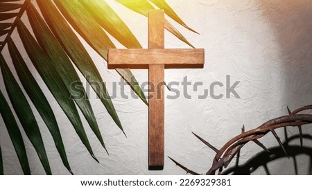 Crown of thorns with wooden cross and palm leaf on light background. Good Friday concept