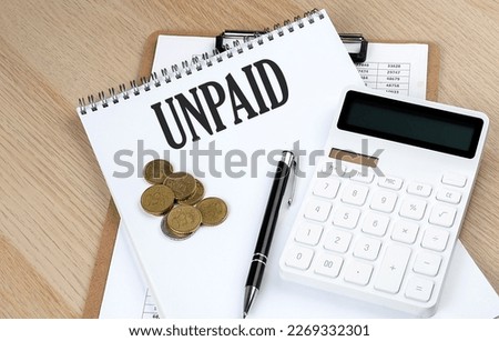 UNPAID text on notebook with chart and calculator and coins, business concept Royalty-Free Stock Photo #2269332301