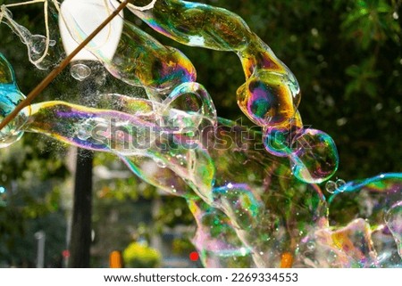 Giant soap bubbles created with ropes and sticks in a park.