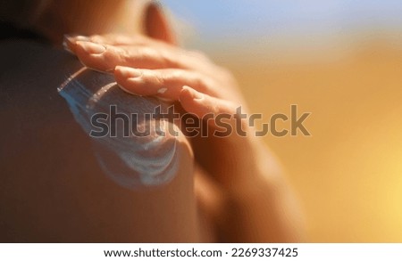 Woman applying sunblock cream on her shoulder. Royalty-Free Stock Photo #2269337425