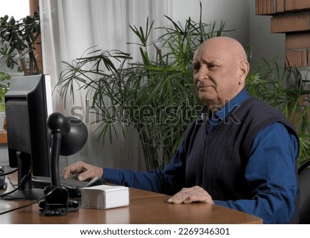 An elderly man, a pensioner sits in front of a computer monitor. Life, life and hobbies of pensioners