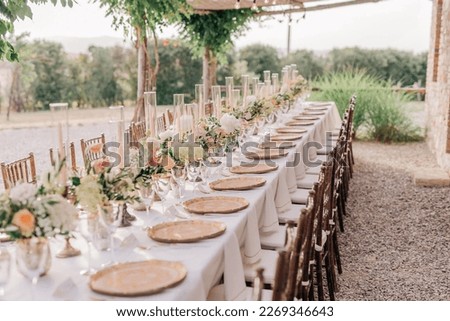 Beautiful elegant romantic wedding dinner decor in pink and gold colors. Long rectangular table with elegant rose gold plates and flower arrangements with pink and white peonies, white hydrangeas Royalty-Free Stock Photo #2269346643