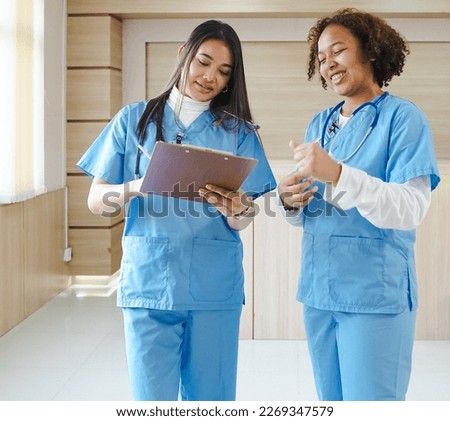Female medical students standing on the job clinical learning at medical school hospital. Multiracial women group intern doctors hold clipboards at internship training. Healthcare business background.