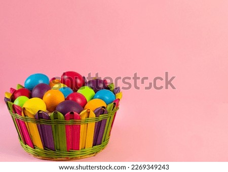 Easter layout . Multi-colored eggs lie in a wicker basket, pink background. Holiday concept, congratulation, postcard, template,copy space, text, moc-up,handmade,spring,decoration,party,poster. Royalty-Free Stock Photo #2269349243