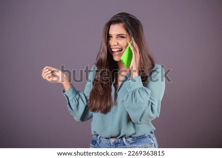 Horizontal photo. Beautiful Brazilian woman, with casual clothes, Jeans and green shirt. on voice call with smartphone.