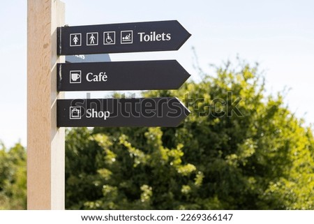 Wooden signs indicating the entrance to the cafe, shop and restroom.