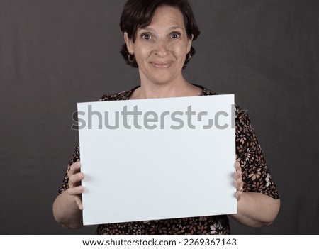 Woman in a print dress holding a white sign. High quality photo with copy space on the sign.