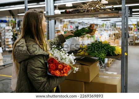 Girl stacks flowers on a shelf in a large flower shop
